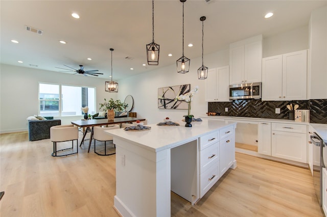 4043 Buck St, Houston, TX 77020 - kitchen featuring stainless steel microwave, recessed lighting, a kitchen island, light wood-type flooring, and tasteful backsplash
