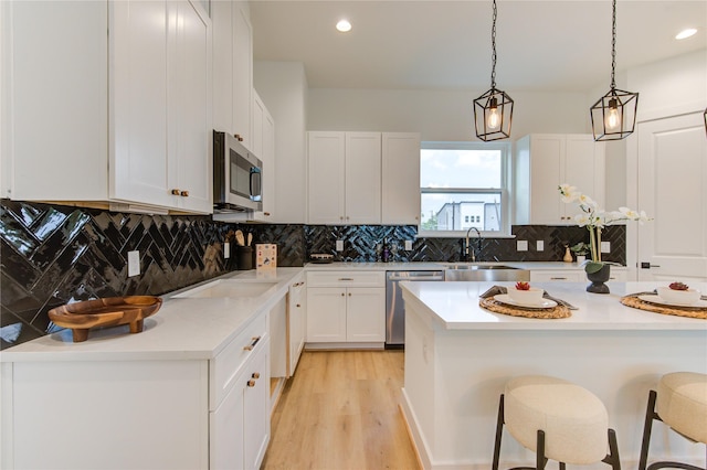 4043 Buck St, Houston, TX 77020 - kitchen with appliances with stainless steel finishes, a breakfast bar area, light countertops, white cabinetry, and decorative light fixtures