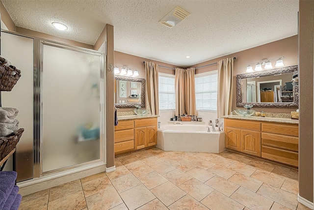 792 W Bayshore Dr, Palacios, TX 77465 - full bath with a textured ceiling, a stall shower, a garden tub, two vanities, and stone tile flooring