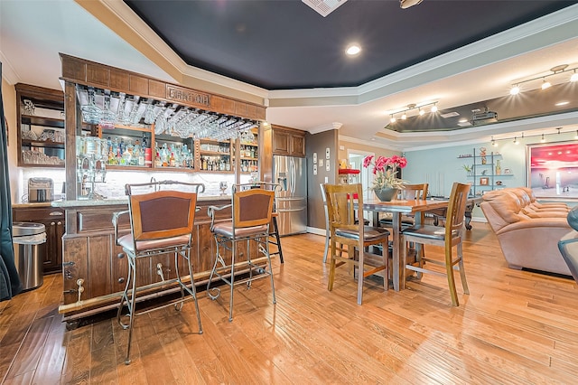 792 W Bayshore Dr, Palacios, TX 77465 - indoor wet bar featuring stainless steel fridge, ornamental molding, a tray ceiling, and light wood-type flooring