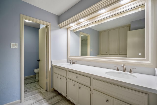 12114 Knobcrest Dr, Houston, TX 77070 - full bathroom with toilet, double vanity, baseboards, and wood finished floors