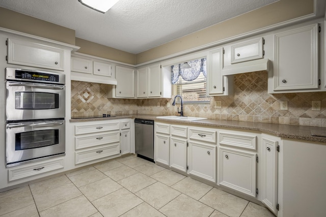 12114 Knobcrest Dr, Houston, TX 77070 - kitchen featuring appliances with stainless steel finishes, a sink, decorative backsplash, light tile patterned flooring, and a textured ceiling