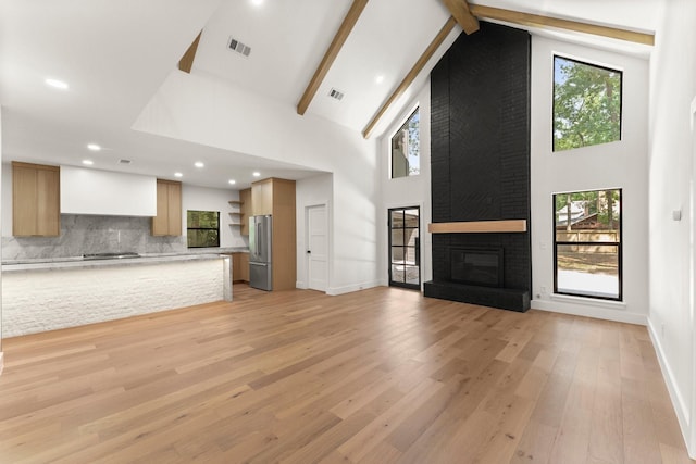 38 Falling Star Ct, The Woodlands, TX 77381 - unfurnished living room with a fireplace, high vaulted ceiling, light wood-style flooring, beam ceiling, and baseboards