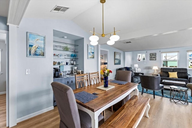 4220 Las Palmas St, Galveston, TX 77554 - dining space featuring light wood-style floors, vaulted ceiling, built in features, and a chandelier