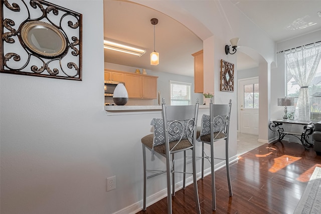 11826 Balmorhea Ln, Sugar Land, TX 77498 - kitchen with arched walkways, light brown cabinetry, wood finished floors, baseboards, and a kitchen bar