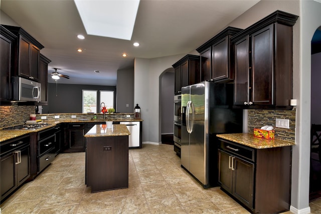 24302 Marisa Ln, Richmond, TX 77406 - kitchen with stainless steel appliances, arched walkways, a peninsula, decorative backsplash, and a kitchen island