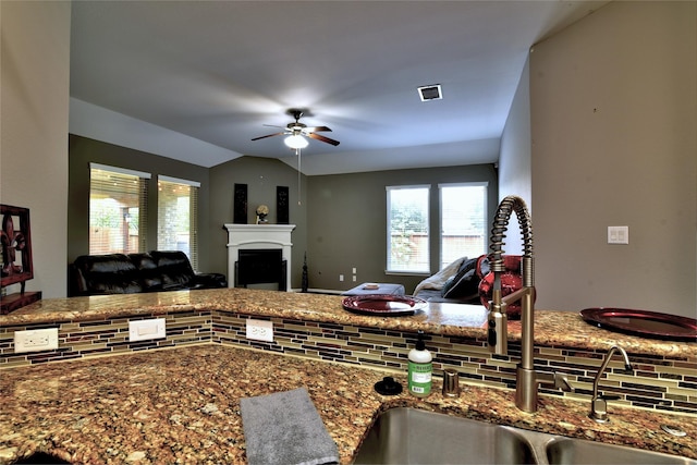 24302 Marisa Ln, Richmond, TX 77406 - kitchen featuring a ceiling fan, a fireplace, open floor plan, dark stone countertops, and vaulted ceiling