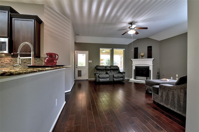 24302 Marisa Ln, Richmond, TX 77406 - living area with vaulted ceiling, ceiling fan, a fireplace with raised hearth, and dark wood-style flooring