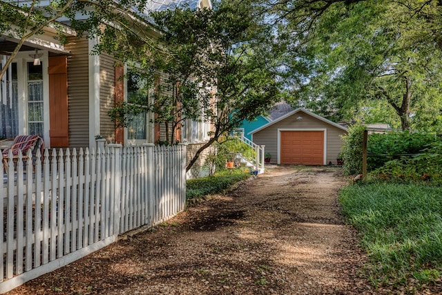 314 W Vulcan St, Brenham, TX 77833 - view of side of home with dirt driveway, a detached garage, and an outbuilding