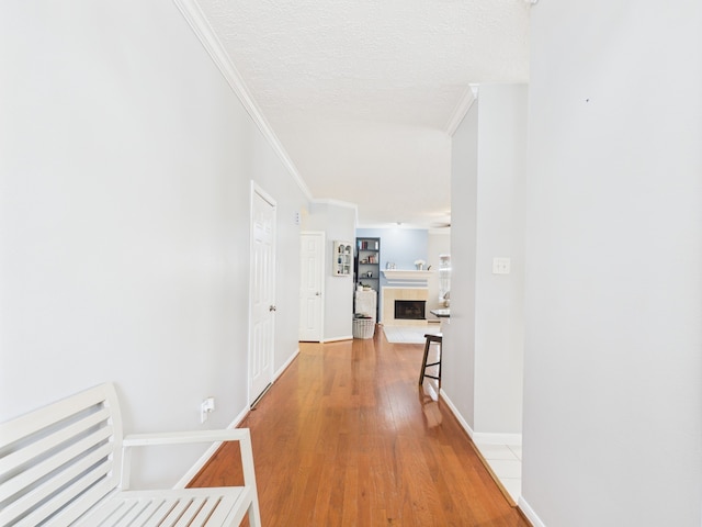 3707 Scenic Valley Dr, Kingwood, TX 77345 - hallway featuring crown molding, light wood-style floors, baseboards, and a textured ceiling