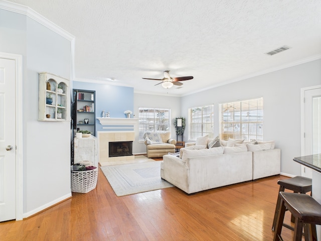 3707 Scenic Valley Dr, Kingwood, TX 77345 - living area with a ceiling fan, hardwood / wood-style flooring, a textured ceiling, a tile fireplace, and ornamental molding