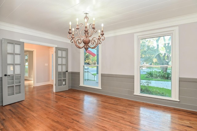 1031 Meyer St, Sealy, TX 77474 - empty room featuring french doors, a chandelier, wood finished floors, ornamental molding, and wainscoting