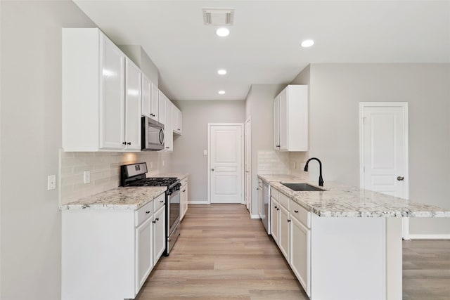 8315 Greys Ln, Houston, TX 77095 - kitchen with stainless steel appliances, a sink, a peninsula, light wood-style floors, and decorative backsplash