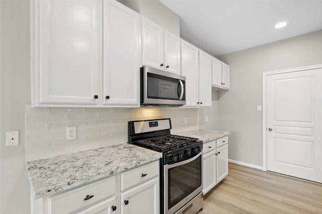 8315 Greys Ln, Houston, TX 77095 - kitchen with appliances with stainless steel finishes, white cabinetry, light wood-type flooring, light stone counters, and backsplash