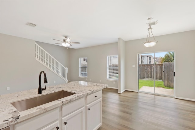 8315 Greys Ln, Houston, TX 77095 - kitchen featuring a sink, pendant lighting, a ceiling fan, light wood-type flooring, and light stone counters