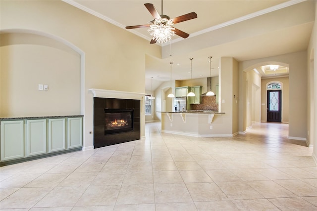 20702 Elderwood Terrace Dr, Richmond, TX 77406 - unfurnished living room with light tile patterned floors, ceiling fan, a tile fireplace, arched walkways, and ornamental molding