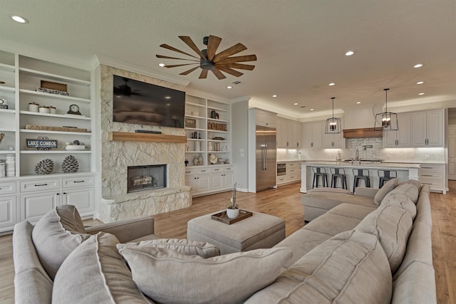131 Sarasota Cir S, Montgomery, TX 77356 - living room with light wood-type flooring, ceiling fan, crown molding, a large fireplace, and recessed lighting