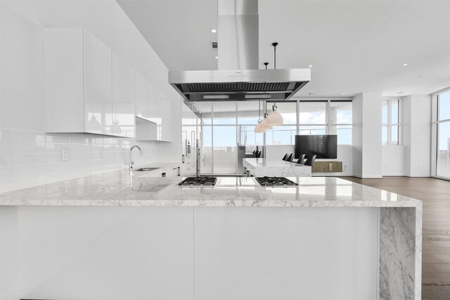 4521 San Felipe St Unit 3101, Houston, TX 77027 - kitchen with extractor fan, white cabinets, decorative backsplash, light stone countertops, and a peninsula