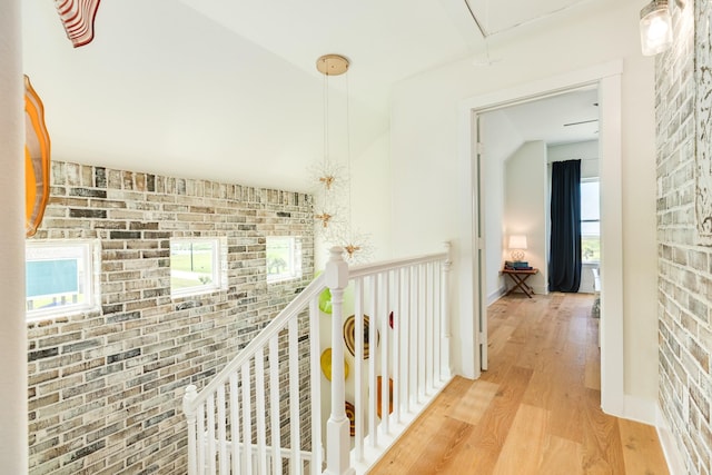 4003 Kiva Rd, Galveston, TX 77554 - hall featuring attic access, light wood-type flooring, brick wall, and an upstairs landing
