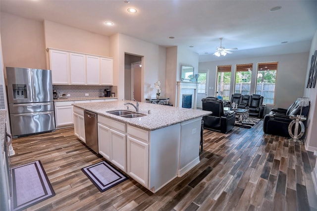 31007 Laurel Creek Ln, Conroe, TX 77385 - kitchen with stainless steel appliances, a sink, a glass covered fireplace, dark wood-type flooring, and recessed lighting