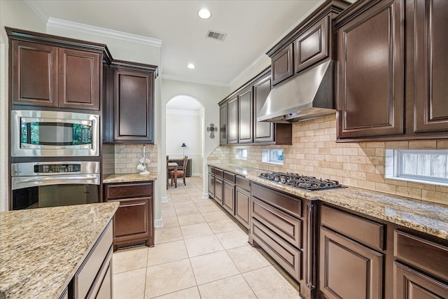 110 Deer Plain Dr, Spring, TX 77389 - kitchen featuring stainless steel appliances, under cabinet range hood, arched walkways, ornamental molding, and light stone countertops