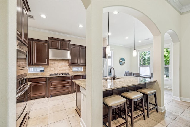 110 Deer Plain Dr, Spring, TX 77389 - kitchen featuring stainless steel appliances, decorative backsplash, a sink, a breakfast bar area, and light stone counters
