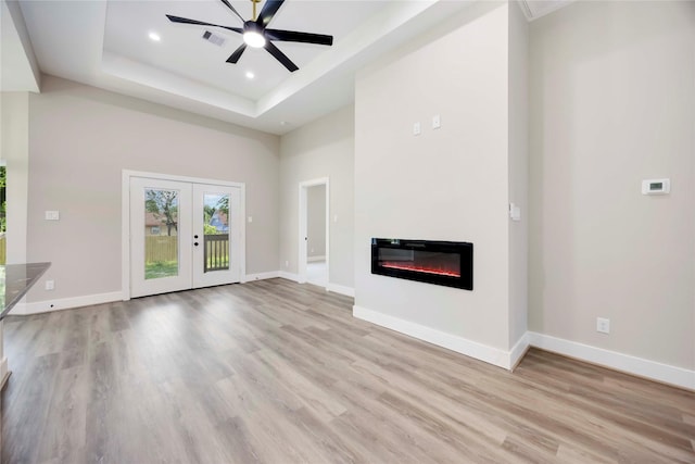 3711 Bain St, Houston, TX 77026 - unfurnished living room with light wood finished floors, a glass covered fireplace, french doors, a raised ceiling, and recessed lighting