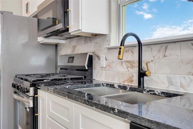 3711 Bain St, Houston, TX 77026 - kitchen featuring stainless steel appliances, a sink, white cabinets, tasteful backsplash, and dark stone counters