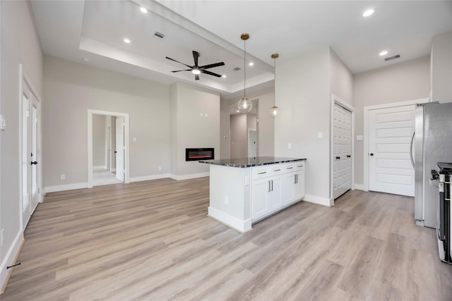 3711 Bain St, Houston, TX 77026 - kitchen featuring open floor plan, a tray ceiling, ceiling fan, dark stone countertops, and white cabinetry