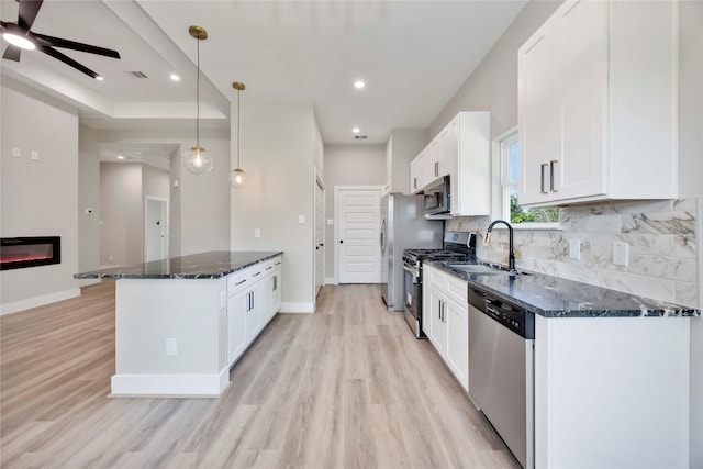 3711 Bain St, Houston, TX 77026 - kitchen with appliances with stainless steel finishes, a sink, light wood finished floors, white cabinetry, and dark stone counters