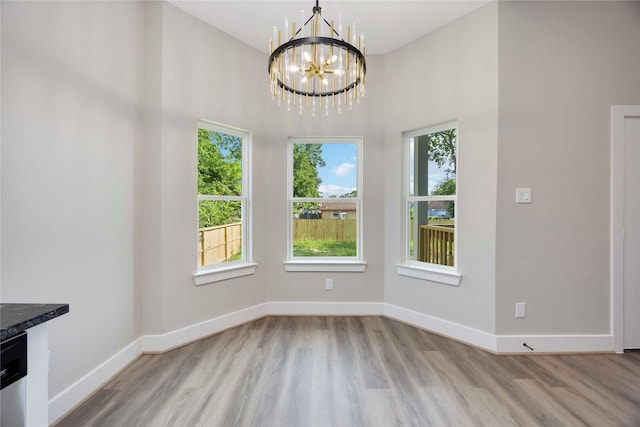 3711 Bain St, Houston, TX 77026 - unfurnished dining area featuring a chandelier, wood finished floors, baseboards, and a towering ceiling