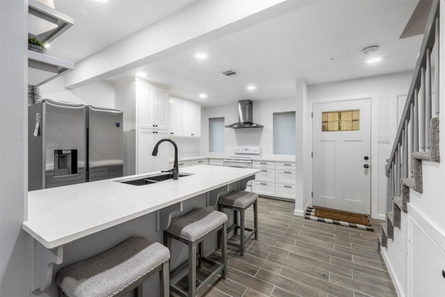 9501 Fondren Rd Unit 9, Houston, TX 77074 - kitchen featuring stainless steel fridge, wall chimney exhaust hood, a sink, white cabinets, and a breakfast bar