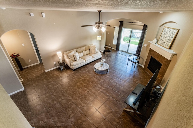 2039 Wembley Way, Rosenberg, TX 77471 - living area with a textured ceiling, arched walkways, a ceiling fan, a fireplace, and baseboards