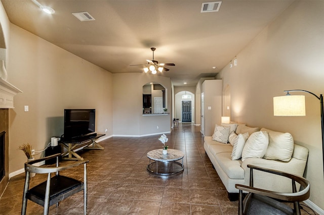 2039 Wembley Way, Rosenberg, TX 77471 - tiled living room with arched walkways, a ceiling fan, a glass covered fireplace, and baseboards