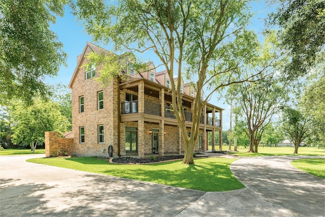 3003 Sky Ranch Dr, Alvin, TX 77511 - view of front of house with a balcony, concrete driveway, a front lawn, and brick siding