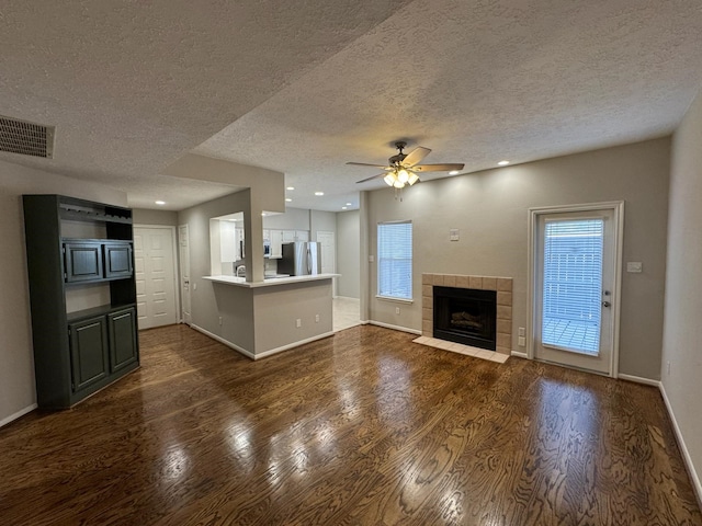 2011 Spenwick Dr Unit 513, Houston, TX 77055 - unfurnished living room with dark wood-style floors, a textured ceiling, baseboards, ceiling fan, and a tiled fireplace
