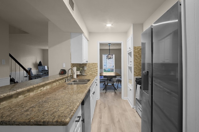 12250 Beamer Rd, Houston, TX 77089 - kitchen with stainless steel appliances, a sink, tasteful backsplash, white cabinets, and light wood-style flooring