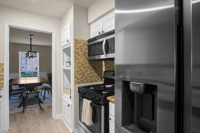 12250 Beamer Rd, Houston, TX 77089 - kitchen with appliances with stainless steel finishes, white cabinets, light wood finished floors, tasteful backsplash, and hanging light fixtures