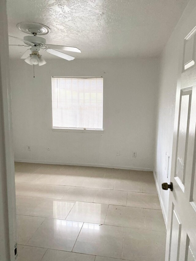 7449 Cook Rd, Houston, TX 77072 - empty room with a ceiling fan, baseboards, light tile patterned floors, and a textured ceiling