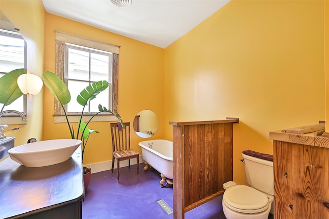 2215 30th St, Galveston, TX 77550 - bathroom with a freestanding tub, toilet, concrete flooring, vanity, and baseboards