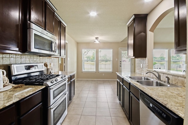 9115 E Lakeside Dr, Magnolia, TX 77354 - kitchen with stainless steel appliances, a sink, backsplash, baseboards, and a textured ceiling