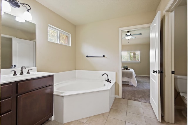 9115 E Lakeside Dr, Magnolia, TX 77354 - ensuite bathroom featuring toilet, a garden tub, vanity, tile patterned flooring, and a ceiling fan