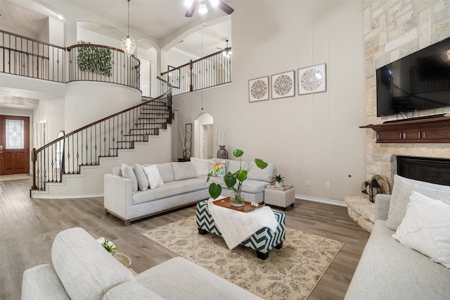 2106 Asbury Ct, Pearland, TX 77581 - living room featuring a high ceiling, stairway, a stone fireplace, baseboards, and ceiling fan