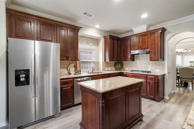 2106 Asbury Ct, Pearland, TX 77581 - kitchen featuring appliances with stainless steel finishes, a sink, under cabinet range hood, crown molding, and light wood finished floors
