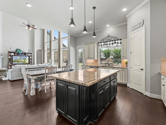 18910 Paddlefish Way, Cypress, TX 77433 - kitchen featuring dark cabinetry, open floor plan, a kitchen island, crown molding, and decorative light fixtures