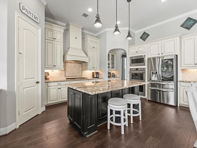 18910 Paddlefish Way, Cypress, TX 77433 - kitchen featuring stainless steel appliances, premium range hood, ornamental molding, arched walkways, and a center island