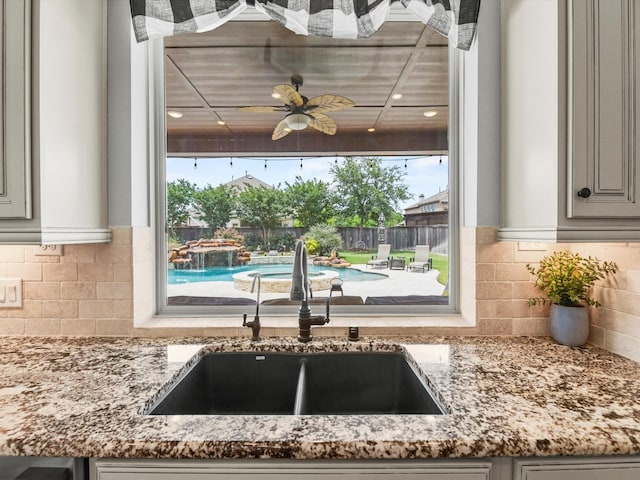 18910 Paddlefish Way, Cypress, TX 77433 - kitchen view of light stone counters, tasteful backsplash, a ceiling fan, and gray cabinets