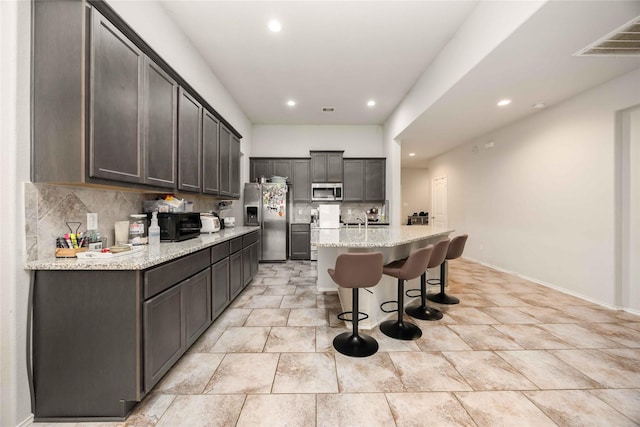 4507 Terrazza Verde Dr, Katy, TX 77493 - kitchen with stainless steel appliances, recessed lighting, a kitchen bar, tasteful backsplash, and a sink