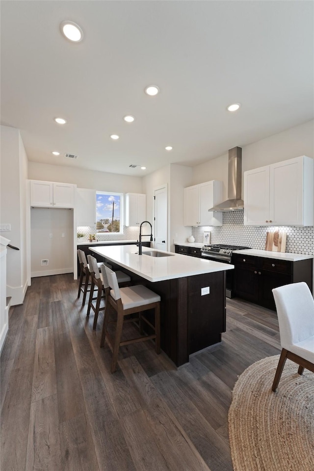 3905 Pinemont Dr Unit G, Houston, TX 77018 - kitchen featuring wall chimney exhaust hood, a sink, a kitchen island with sink, backsplash, and white cabinetry