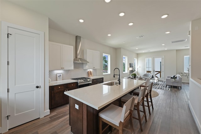 3905 Pinemont Dr Unit G, Houston, TX 77018 - kitchen featuring wall chimney exhaust hood, a sink, gas stove, wood finished floors, and a kitchen breakfast bar